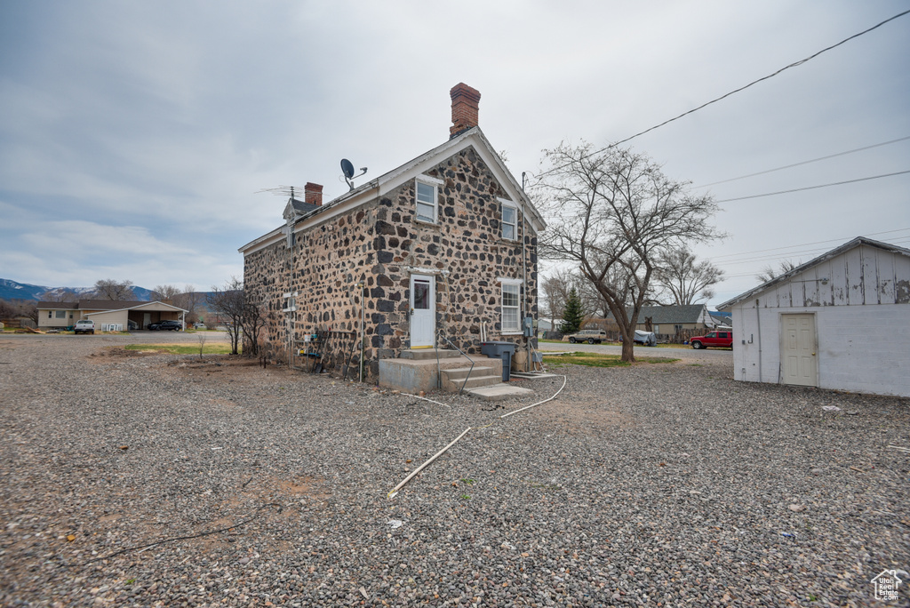 Rear view of property featuring stone siding and a chimney