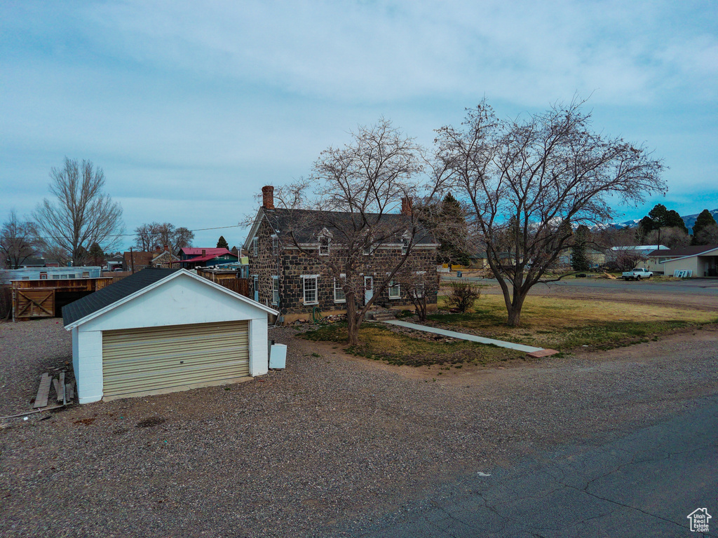 View of front of house with an outbuilding, a detached garage, and a chimney