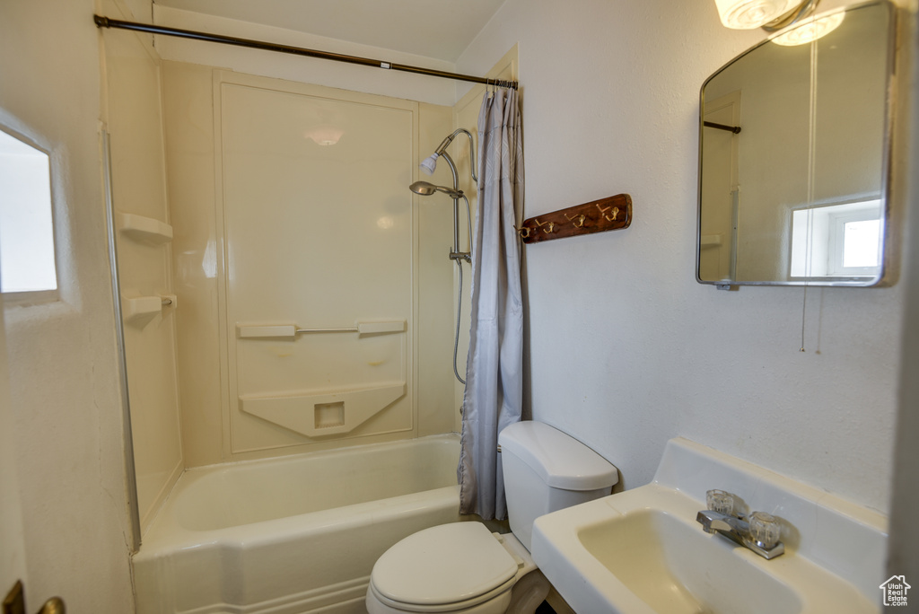 Full bathroom featuring a sink, toilet, shower / tub combo with curtain, and a healthy amount of sunlight