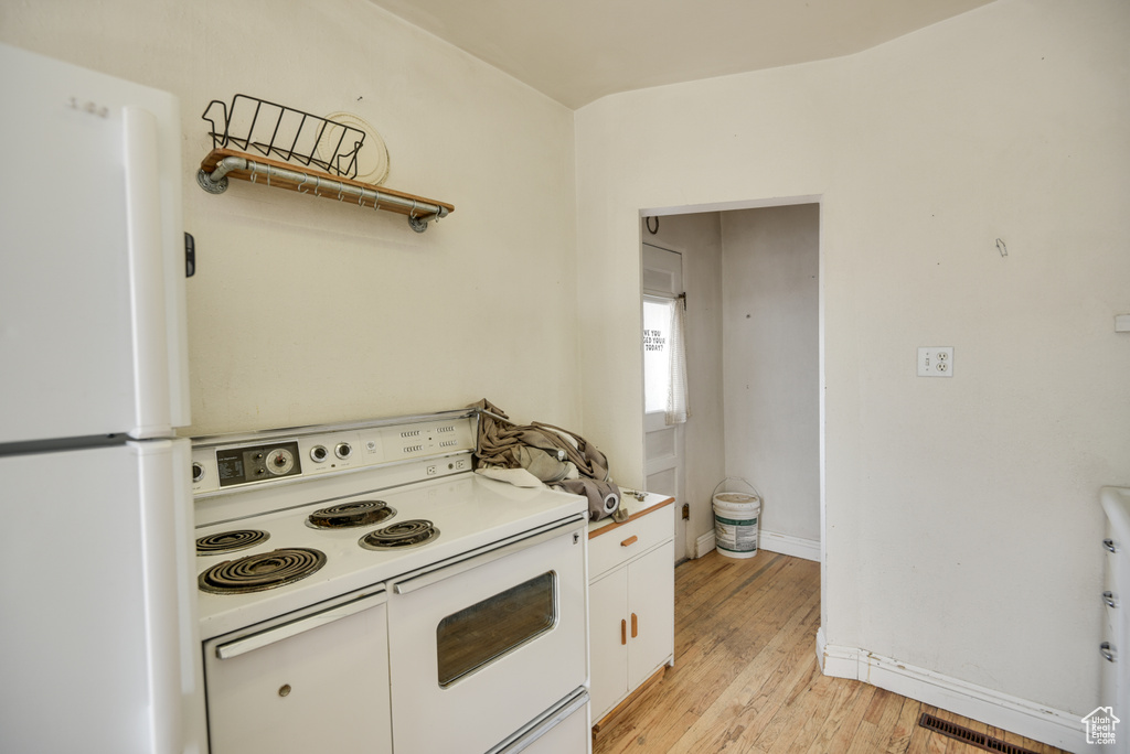 Kitchen featuring baseboards, white appliances, light wood-style flooring, white cabinets, and visible vents