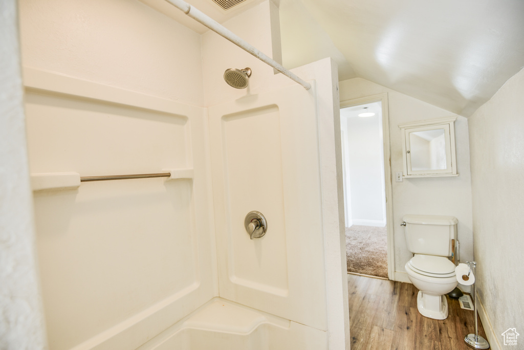 Full bath featuring a shower, wood finished floors, lofted ceiling, and toilet