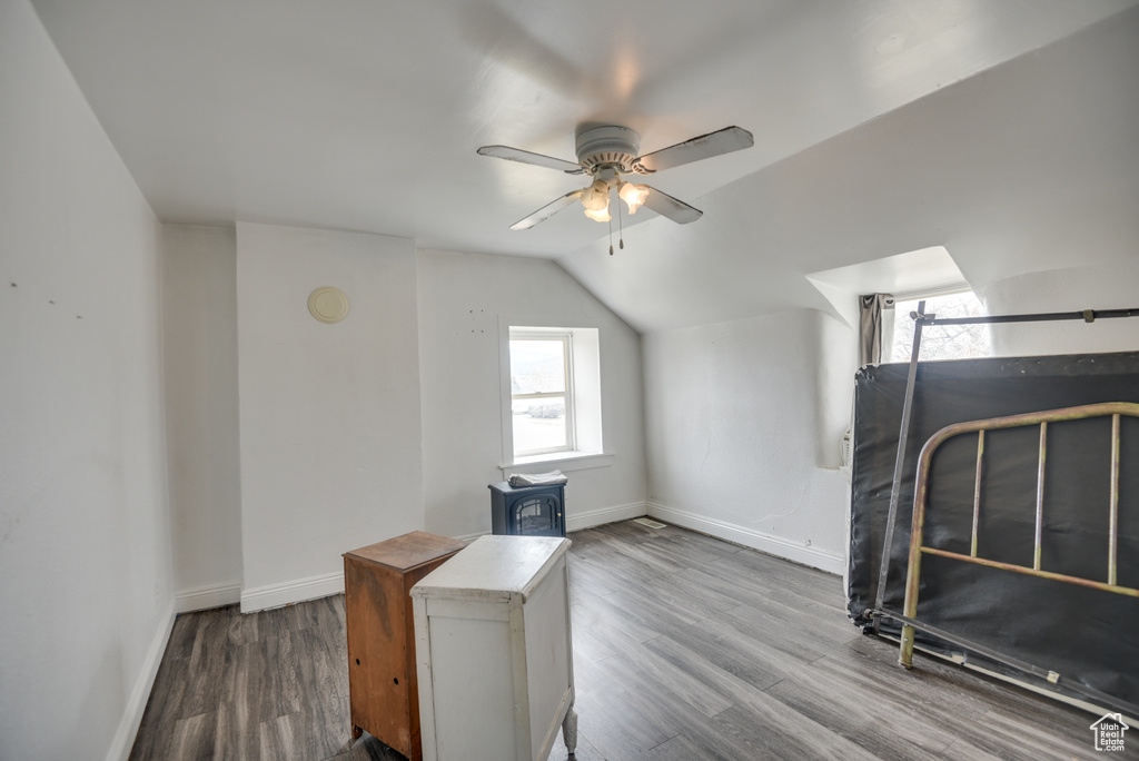 Additional living space with lofted ceiling, baseboards, wood finished floors, and ceiling fan