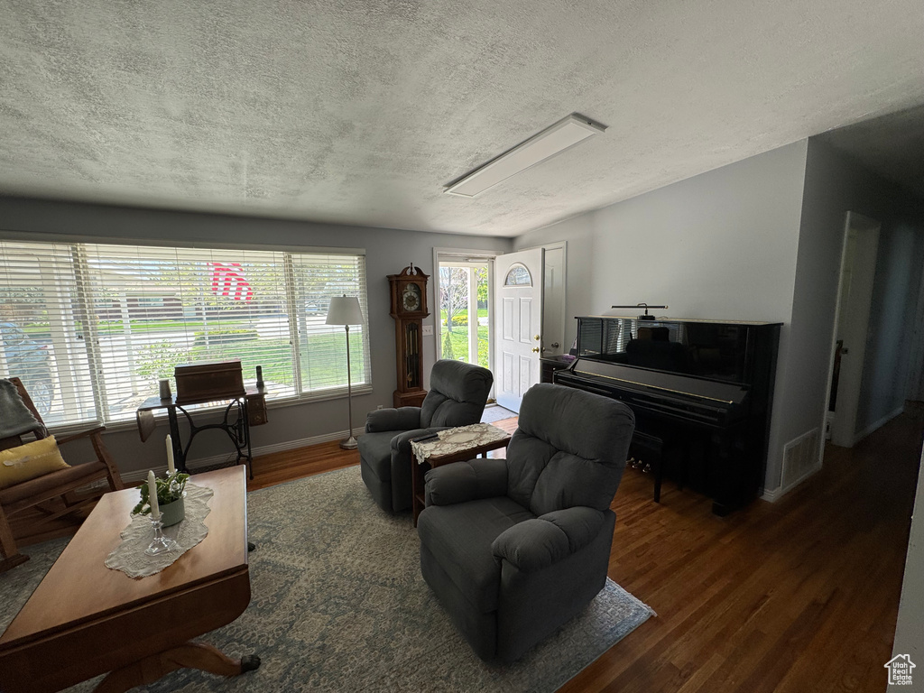 Living area with a textured ceiling, wood finished floors, and baseboards
