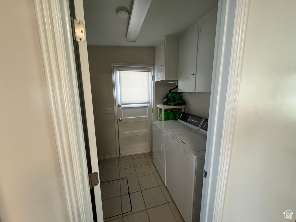 Washroom featuring separate washer and dryer, light tile patterned floors, and cabinet space