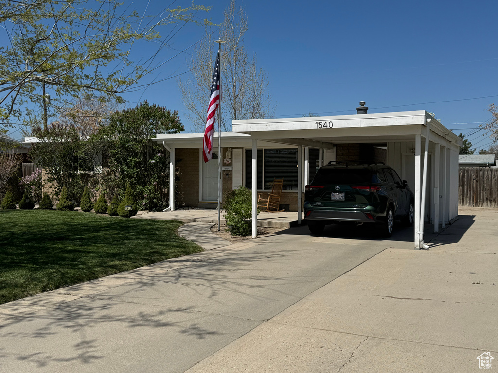 View of front of property with driveway, fence, and a front lawn