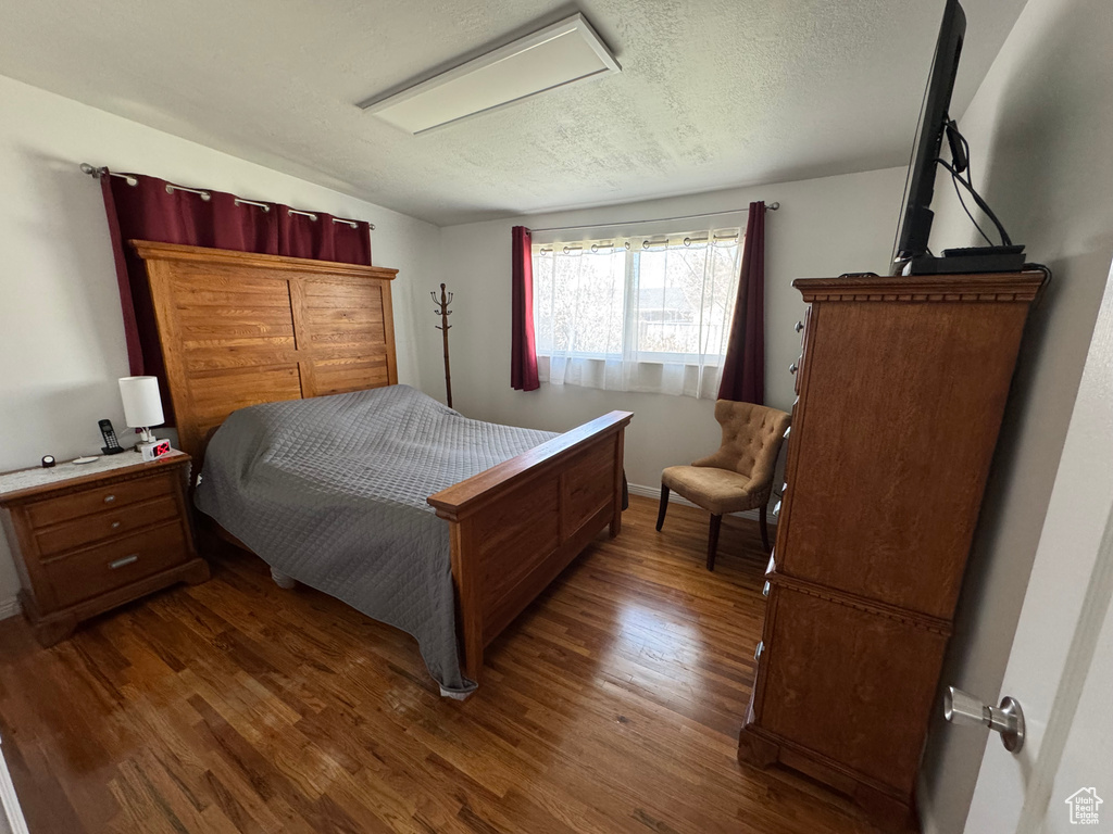 Bedroom featuring dark wood-type flooring, a textured ceiling, and baseboards