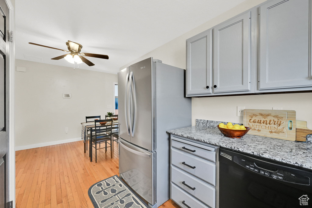 Kitchen with dishwasher, freestanding refrigerator, ceiling fan, gray cabinets, and light wood-style flooring