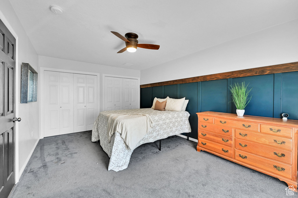 Bedroom featuring multiple closets, carpet, and ceiling fan