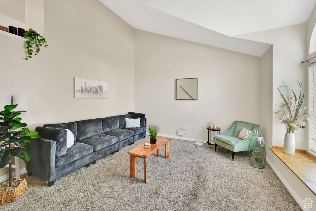 Carpeted living area with baseboards and lofted ceiling