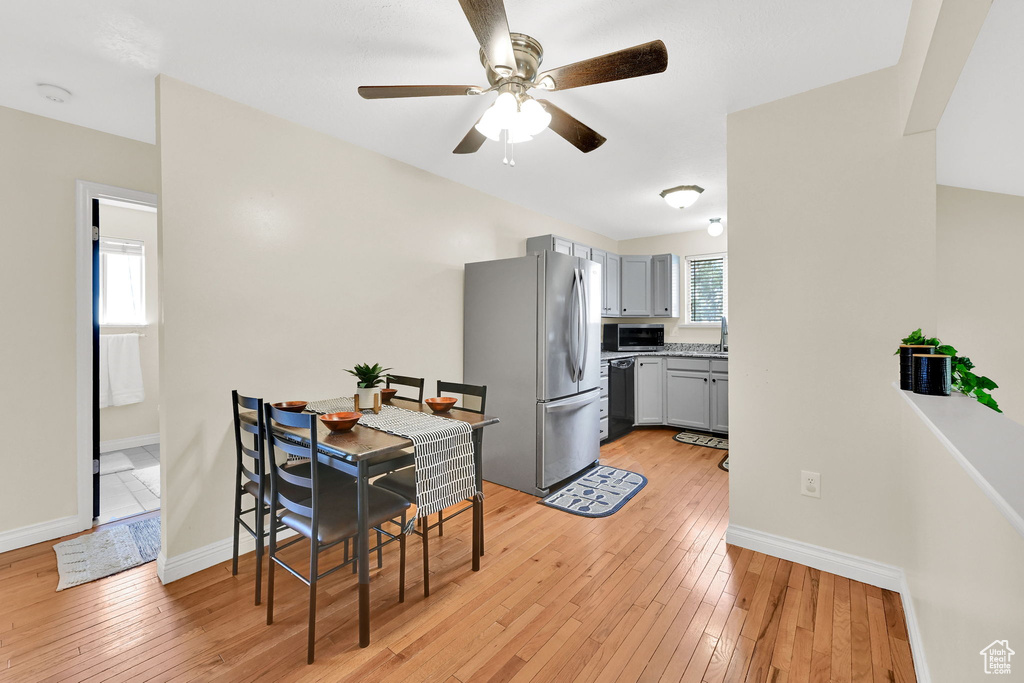 Dining space with a ceiling fan, light wood-type flooring, and baseboards