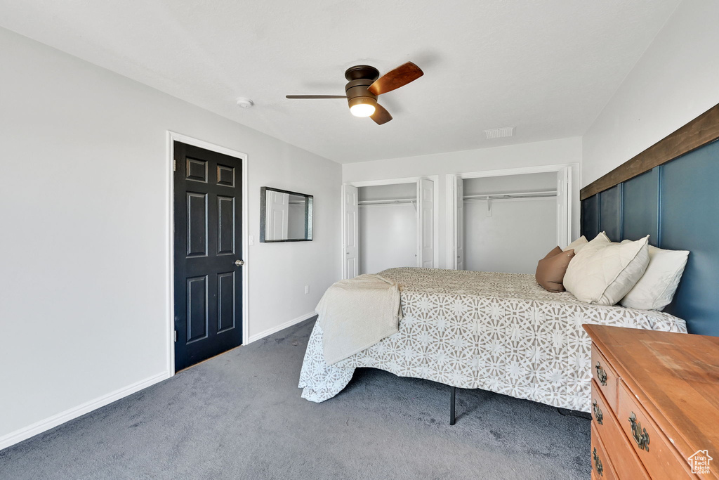 Bedroom with carpet flooring, two closets, baseboards, and a ceiling fan