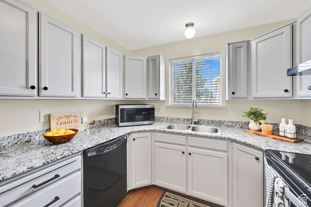 Kitchen featuring dishwasher, stainless steel microwave, a sink, electric range, and light wood-style floors