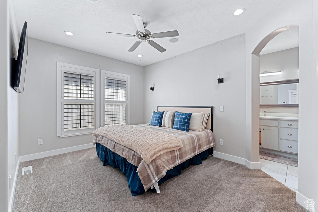 Bedroom with ceiling fan, carpet, arched walkways, visible vents, and baseboards