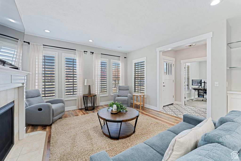 Living room featuring recessed lighting, a tile fireplace, baseboards, and wood finished floors