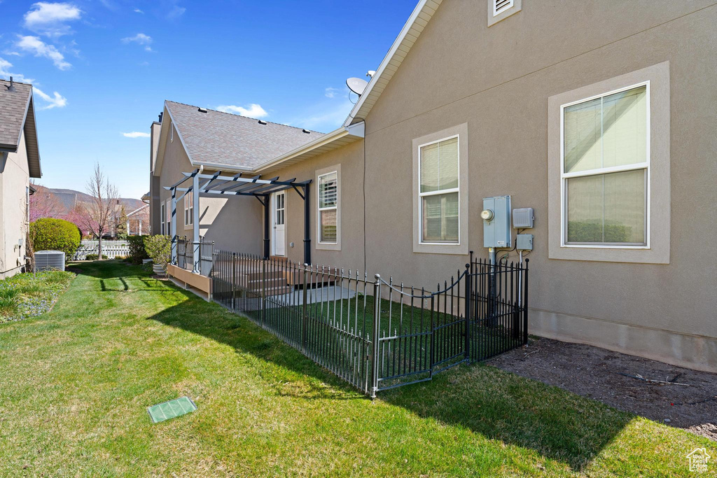 Rear view of house with a yard, a pergola, stucco siding, and central air condition unit