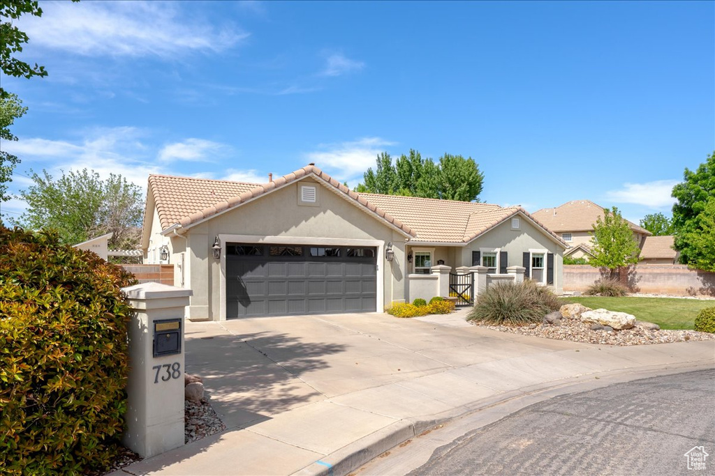 Ranch-style house featuring stucco siding, fence, a tile roof, an attached garage, and concrete driveway