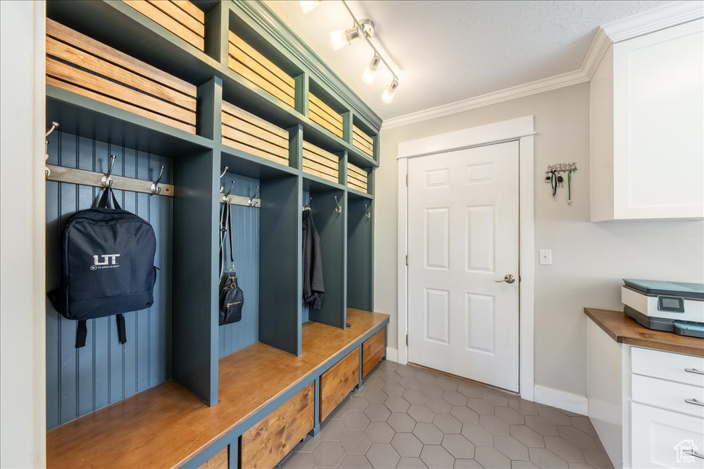 Mudroom with baseboards, crown molding, and dark tile patterned flooring