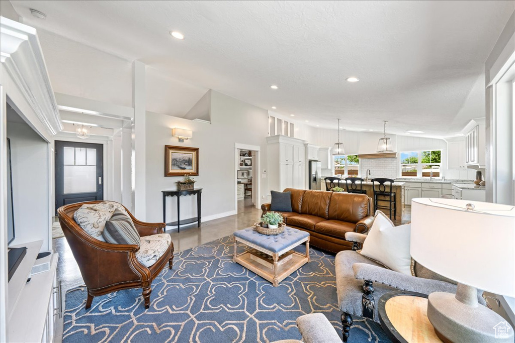 Living room featuring recessed lighting, concrete floors, baseboards, and vaulted ceiling