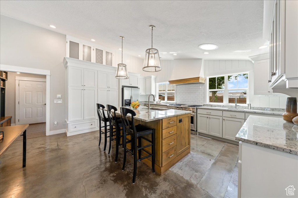 Kitchen with custom range hood, recessed lighting, a sink, and appliances with stainless steel finishes