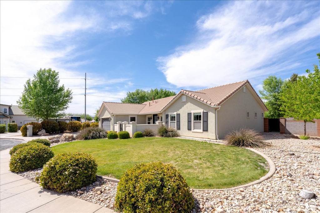 Ranch-style house with stucco siding, a front lawn, a tile roof, a garage, and fence