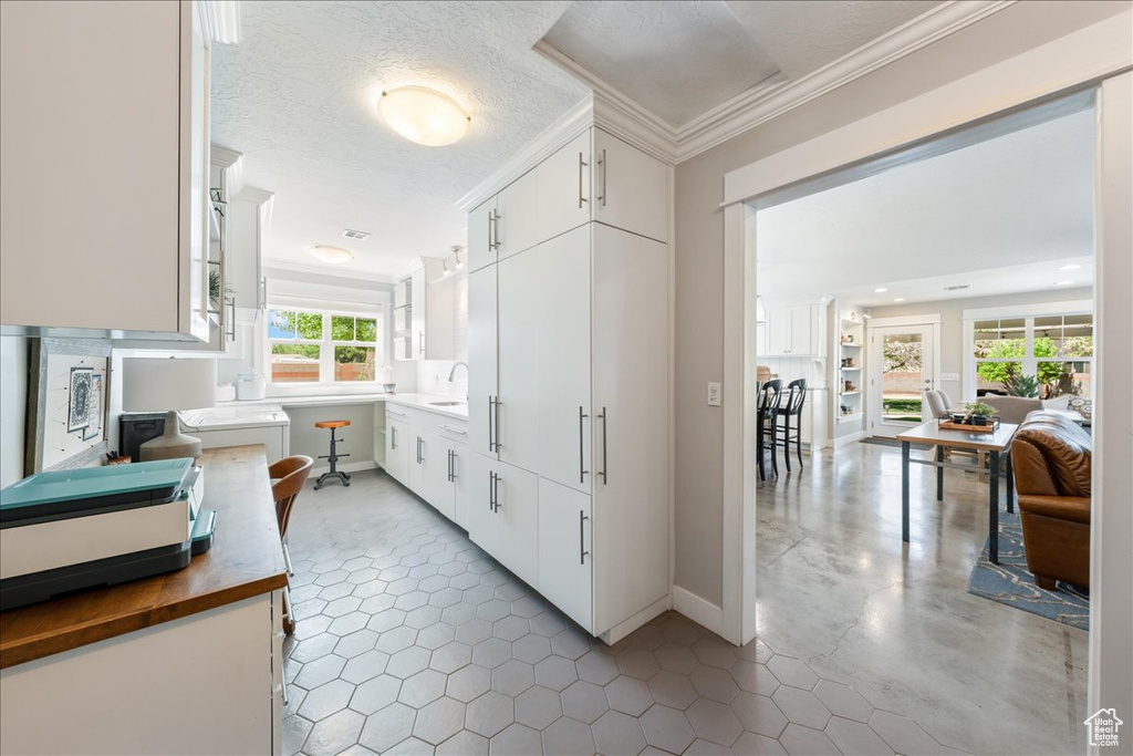 Hallway featuring tile patterned floors, baseboards, and ornamental molding