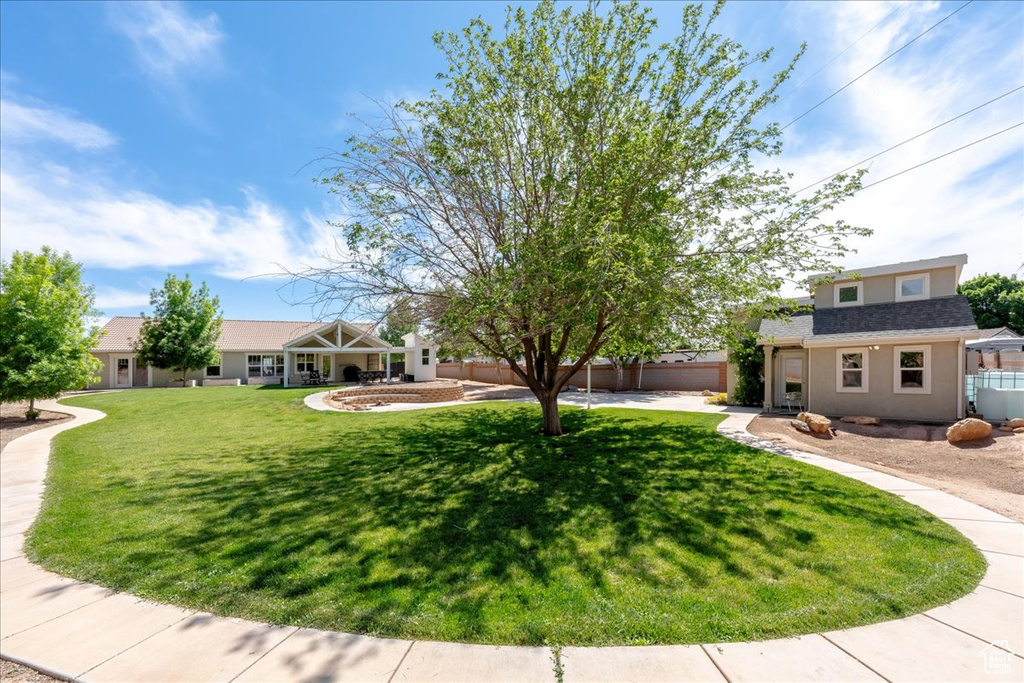 View of front facade featuring a front lawn, fence, driveway, and stucco siding