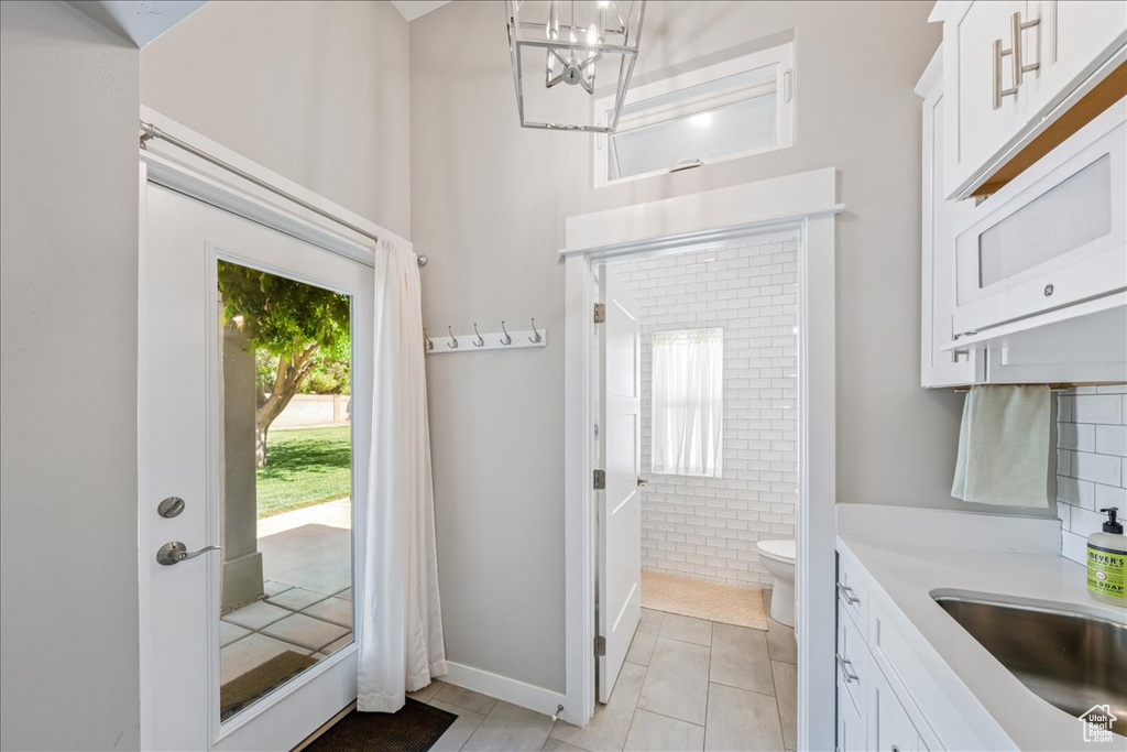 Bathroom with an inviting chandelier, vanity, a towering ceiling, tile patterned flooring, and toilet