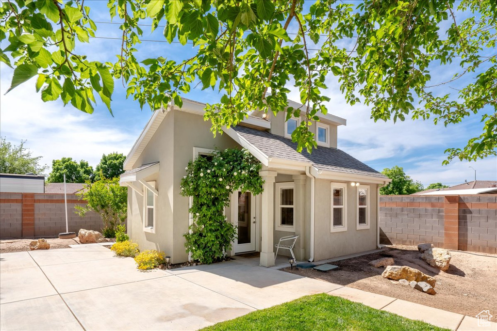 View of front of property with a patio area, fence, and stucco siding
