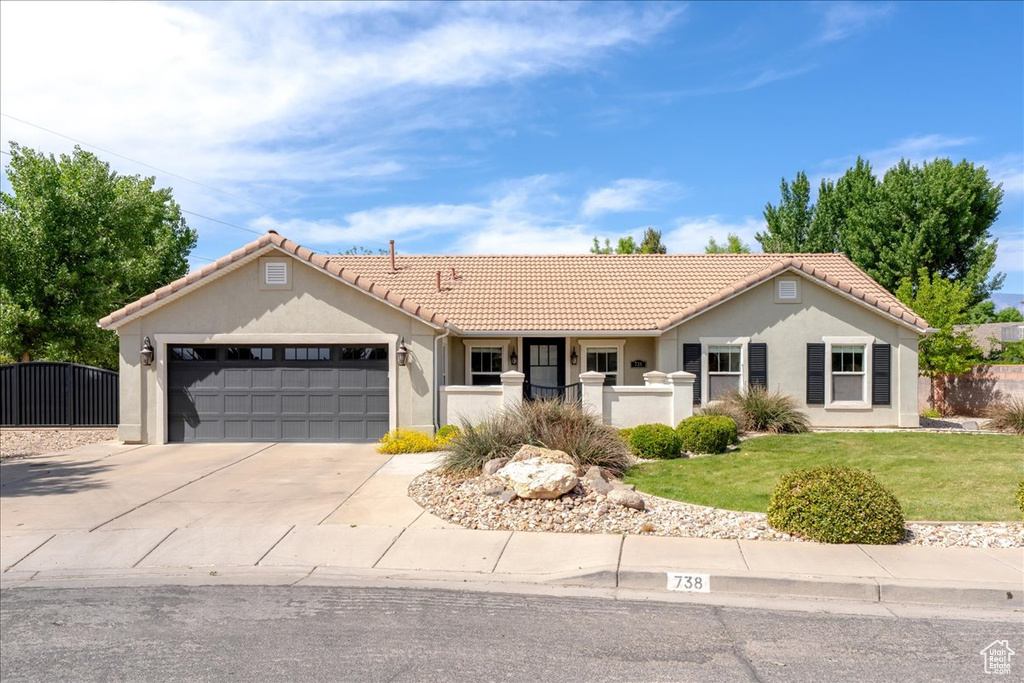 Ranch-style home with stucco siding, driveway, a tile roof, a garage, and fence