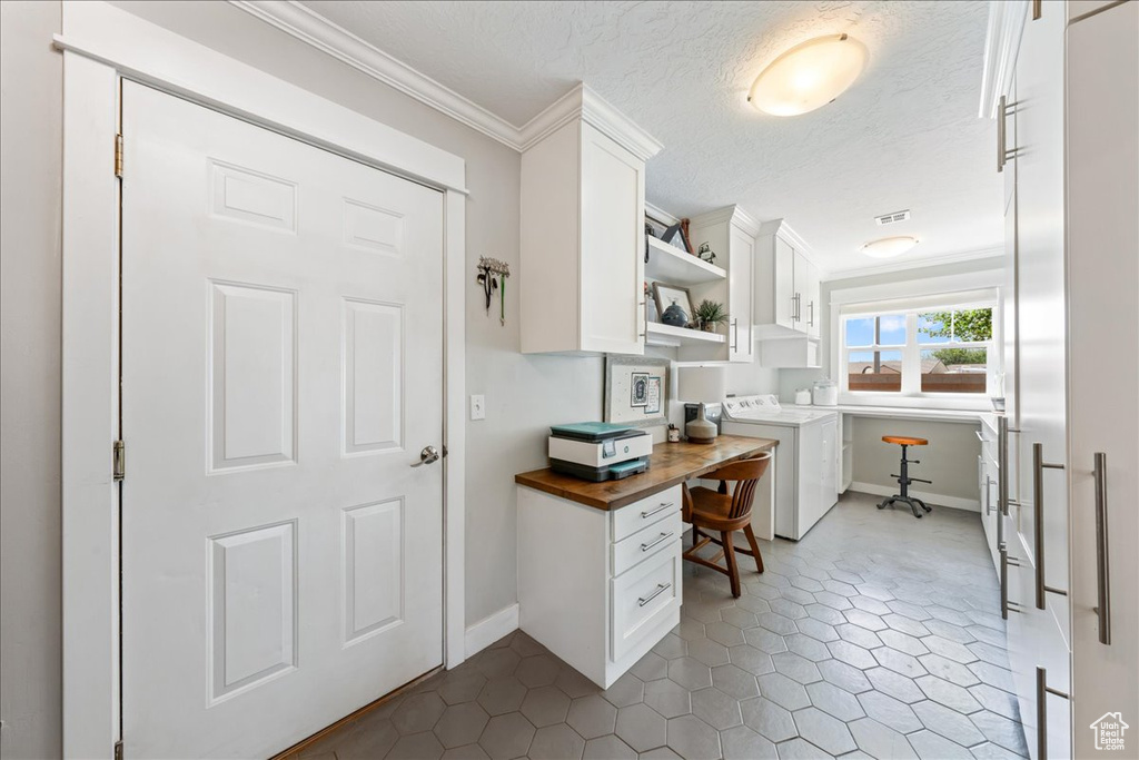 Office space featuring washer / clothes dryer, a textured ceiling, ornamental molding, built in study area, and baseboards