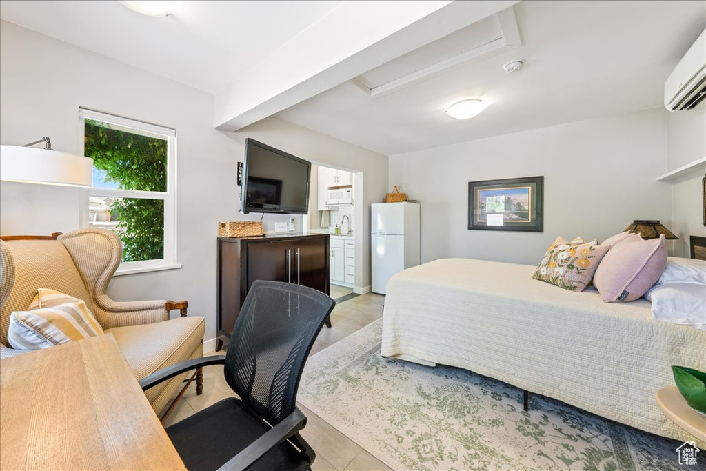 Bedroom featuring attic access, freestanding refrigerator, light tile patterned flooring, a wall unit AC, and a sink