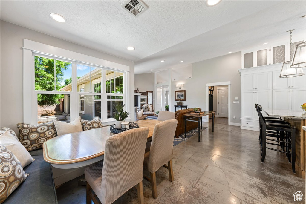 Dining area featuring a textured ceiling, concrete flooring, visible vents, and recessed lighting