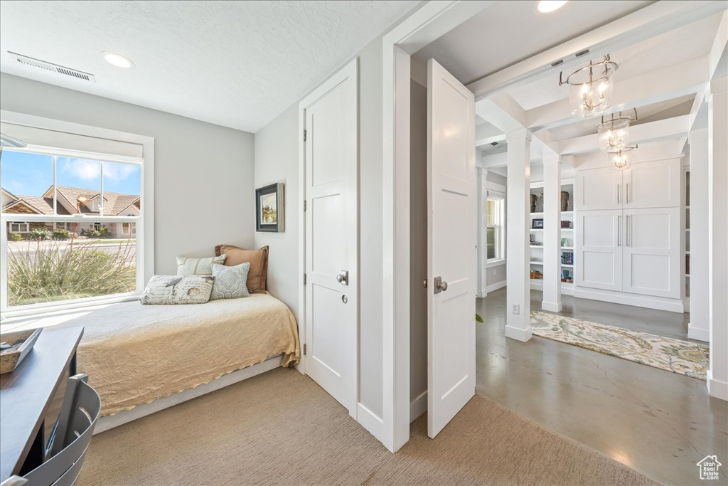 Bedroom with decorative columns, an inviting chandelier, finished concrete floors, visible vents, and recessed lighting