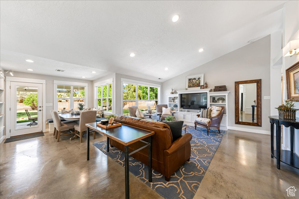 Living area featuring finished concrete floors, baseboards, vaulted ceiling, and recessed lighting
