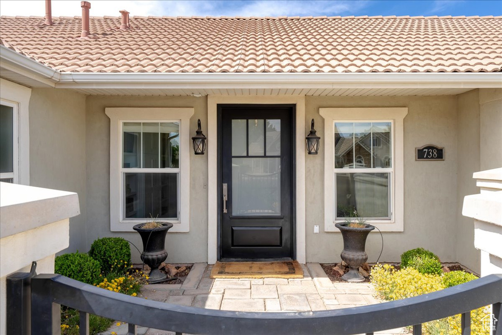 View of exterior entry with stucco siding and a tiled roof