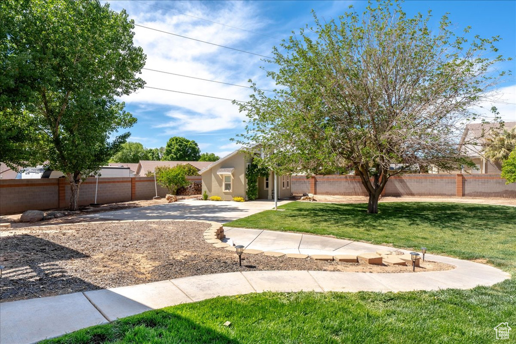 View of front of home featuring a front yard, a patio, a fenced backyard, and stucco siding