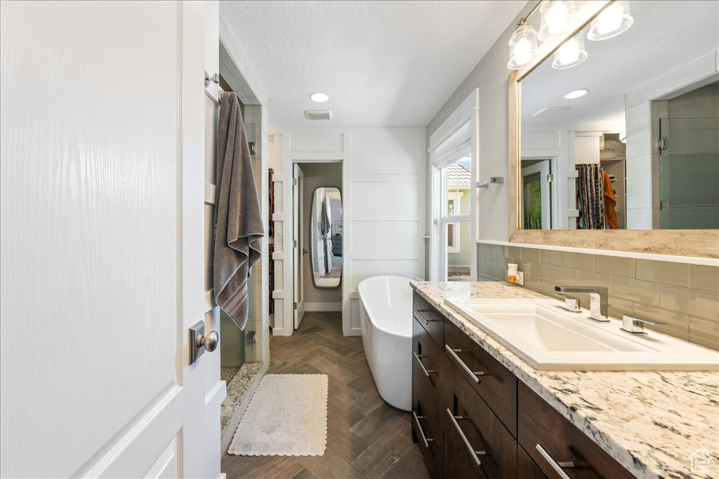 Bathroom featuring tasteful backsplash, vanity, a stall shower, visible vents, and a freestanding bath