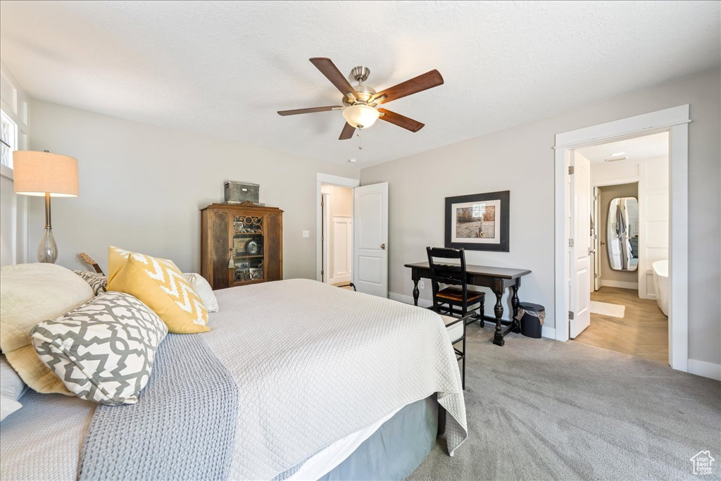 Bedroom with light carpet, ensuite bathroom, baseboards, and a ceiling fan