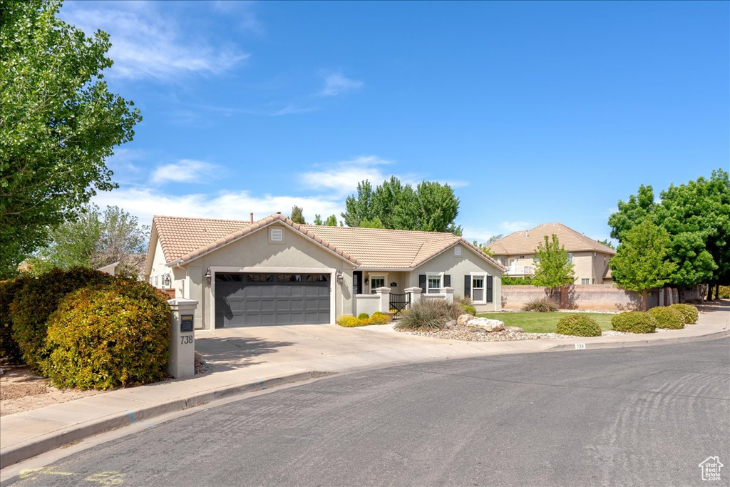 Ranch-style home with a garage, driveway, stucco siding, and a tile roof