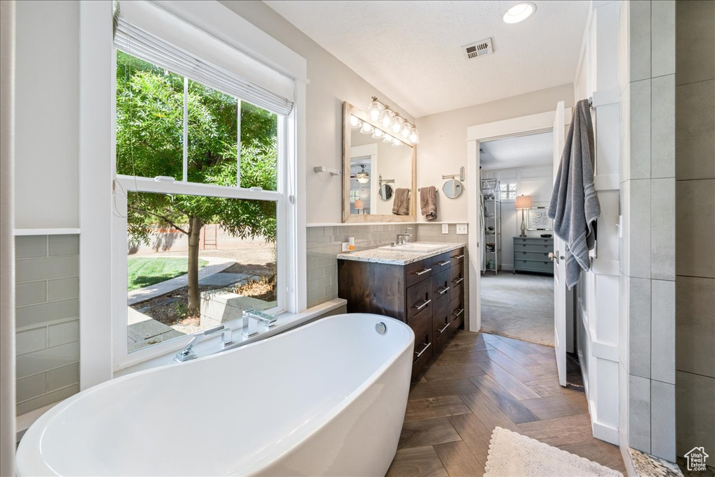 Bathroom featuring tasteful backsplash, vanity, recessed lighting, visible vents, and a freestanding bath