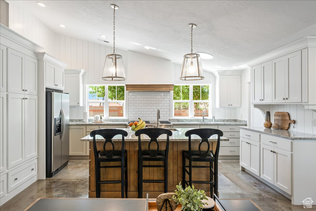 Kitchen featuring plenty of natural light, white cabinetry, backsplash, and stainless steel fridge