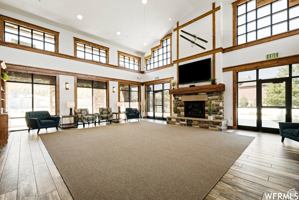 Living room featuring high vaulted ceiling, wood finished floors, plenty of natural light, a stone fireplace, and recessed lighting