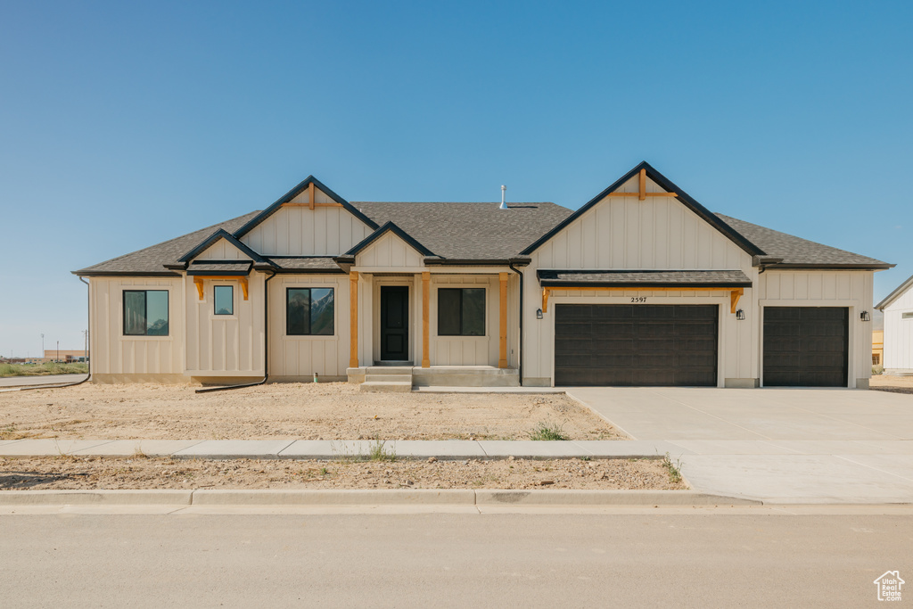 Modern farmhouse style home with a garage, board and batten siding, concrete driveway, and roof with shingles