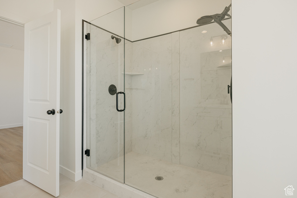 Bathroom with a marble finish shower and baseboards