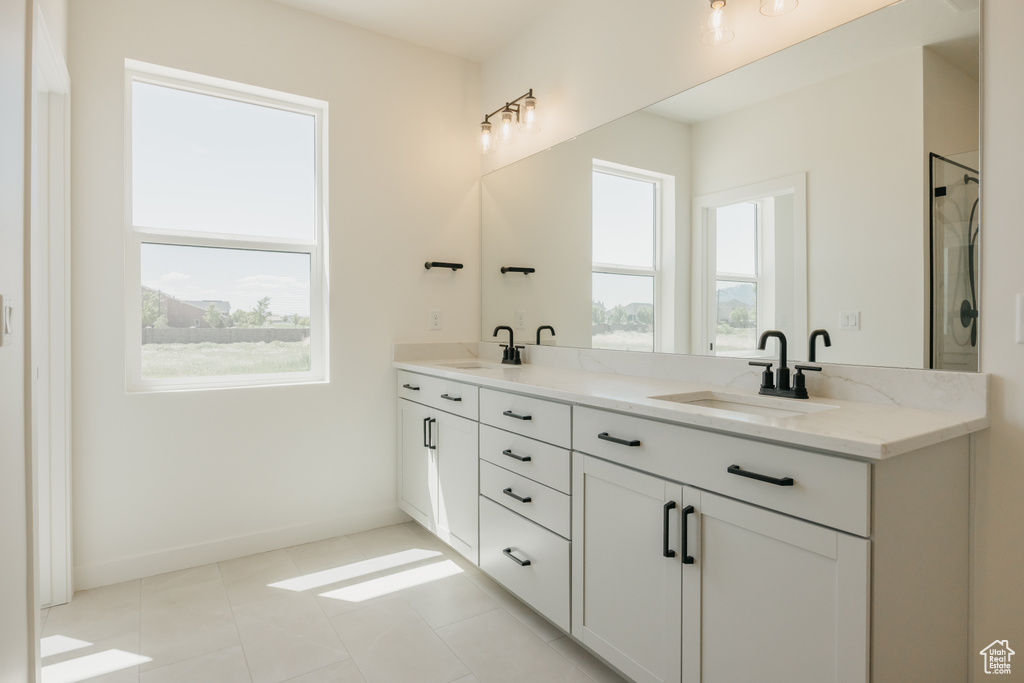 Bathroom featuring double vanity, an enclosed shower, and baseboards