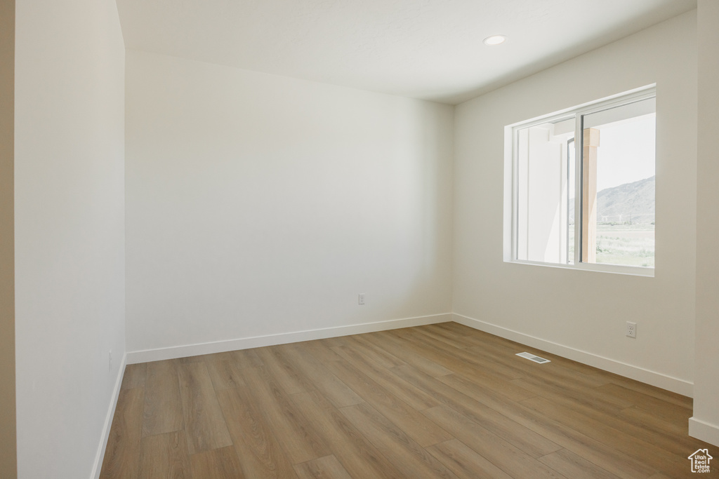 Empty room with light wood finished floors, baseboards, and recessed lighting