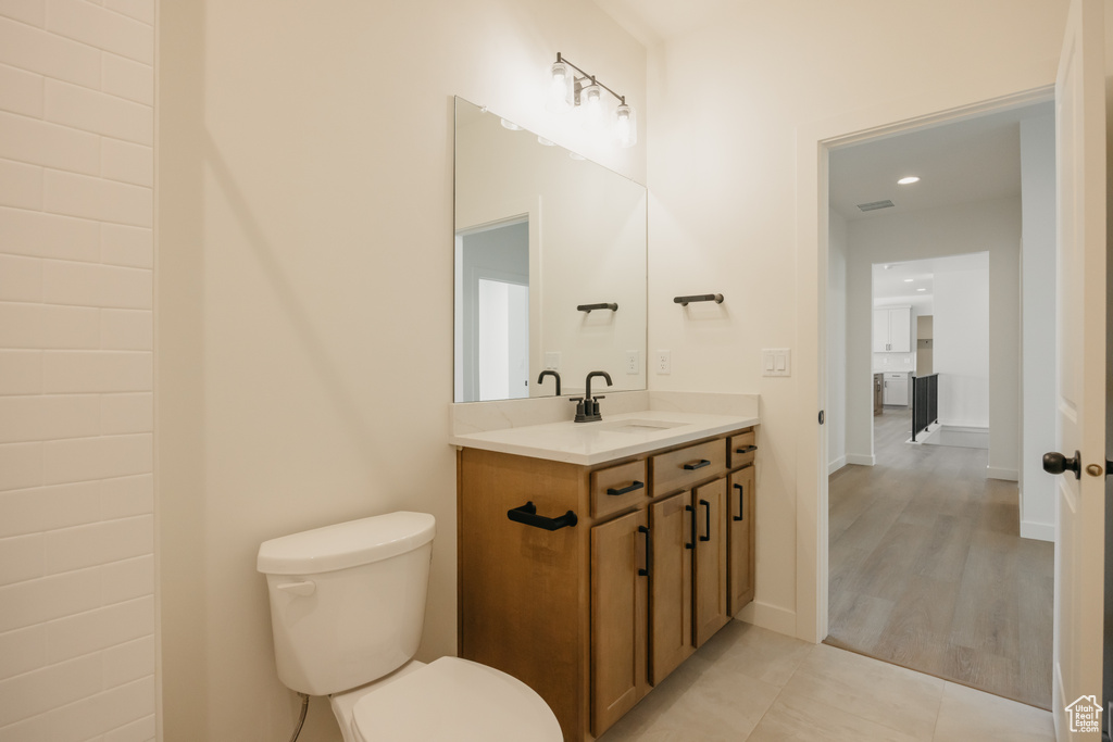 Half bath featuring toilet, vanity, recessed lighting, and tile patterned floors