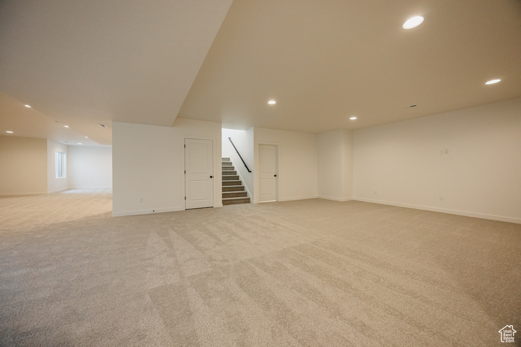Basement featuring recessed lighting, light colored carpet, stairs, and baseboards