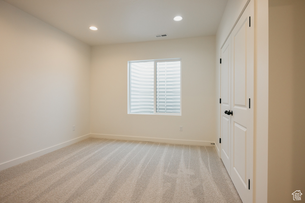 Unfurnished bedroom featuring light colored carpet, baseboards, recessed lighting, and a closet