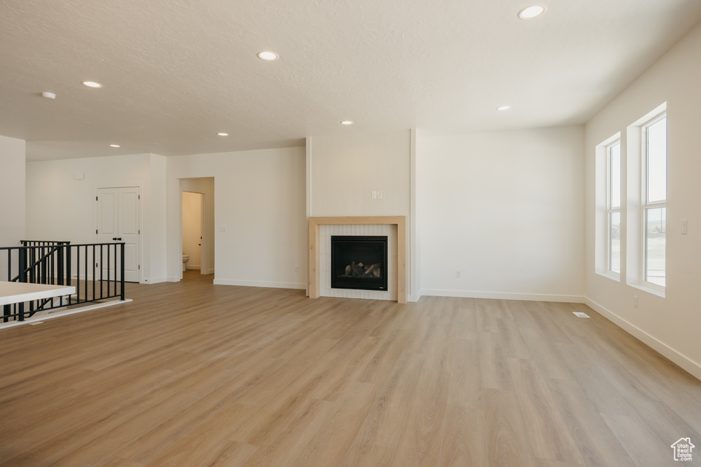 Unfurnished living room with recessed lighting, light wood-style flooring, baseboards, and a fireplace